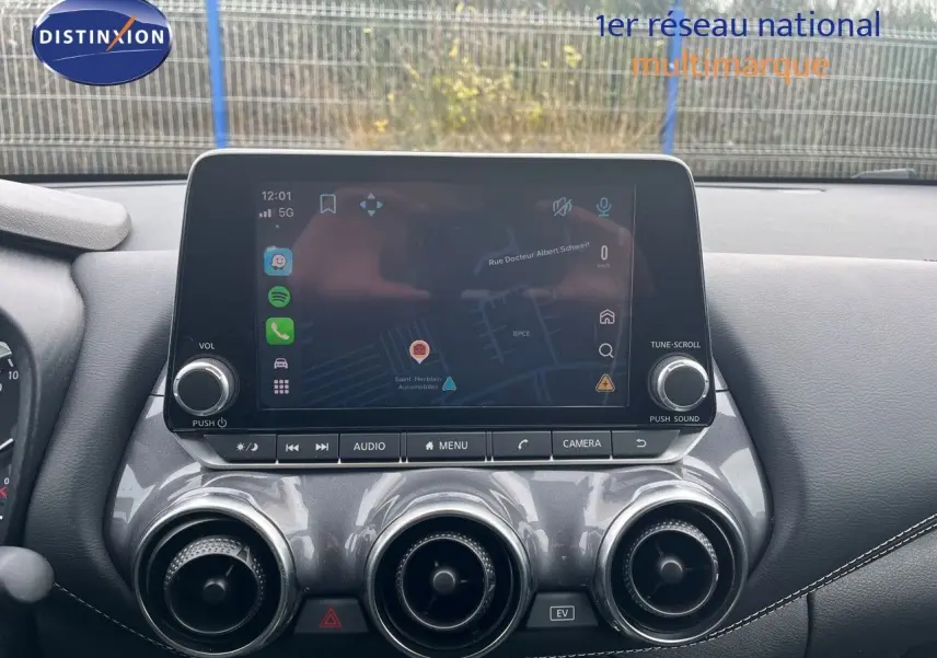 Vue rapprochée de la console centrale du Nissan Juke 2024, écran tactile affichant la navigation et aérateurs ronds chromés.