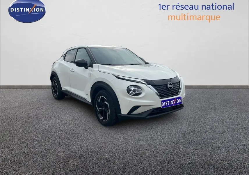 Nissan Juke blanc nacré métal en 3/4 avant droit, avec jantes noires et toit contrasté noir.