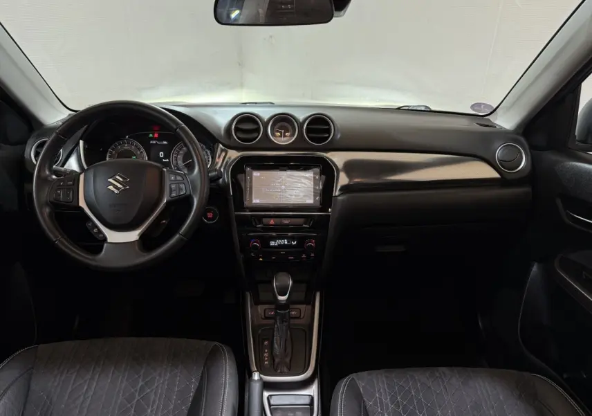 Intérieur noir du Suzuki Vitara 2022 vu de face, tableau de bord avec écran tactile et volant multifonctions cuir.