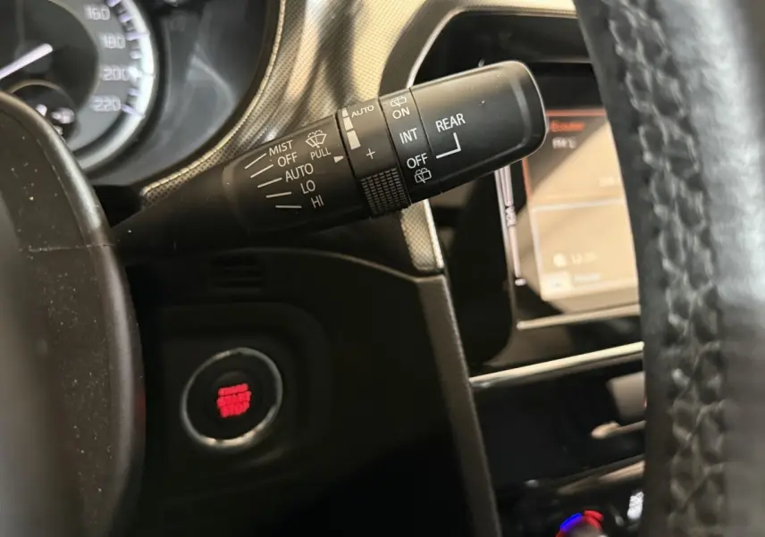 Gros plan sur la manette d'essuie-glace et le bouton start/stop rouge du tableau de bord noir du Suzuki Vitara 2022.