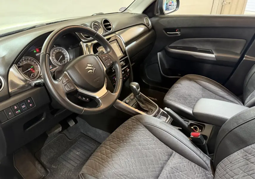 Intérieur noir du Suzuki Vitara 2022 vu côté conducteur, volant cuir multifonctions et console centrale avec boîte auto.