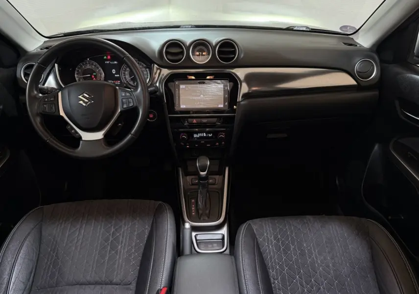 Vue intérieure avant du Suzuki Vitara 1.5 Dualjet hybrid STYLE avec tableau de bord noir et écran tactile central.