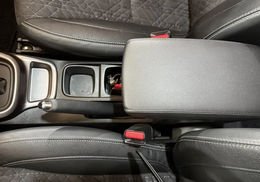 Vue plongeante sur la console centrale noire du Suzuki Vitara 2022, avec frein à main et accoudoir en cuir.