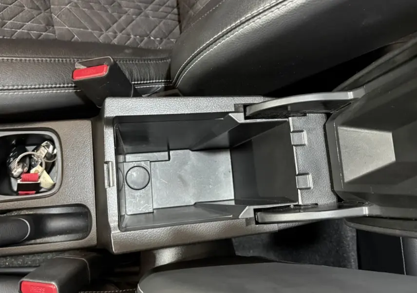 Vue plongeante sur la console centrale noire ouverte du Suzuki Vitara 1.5 Hybrid avec sièges en cuir noir.