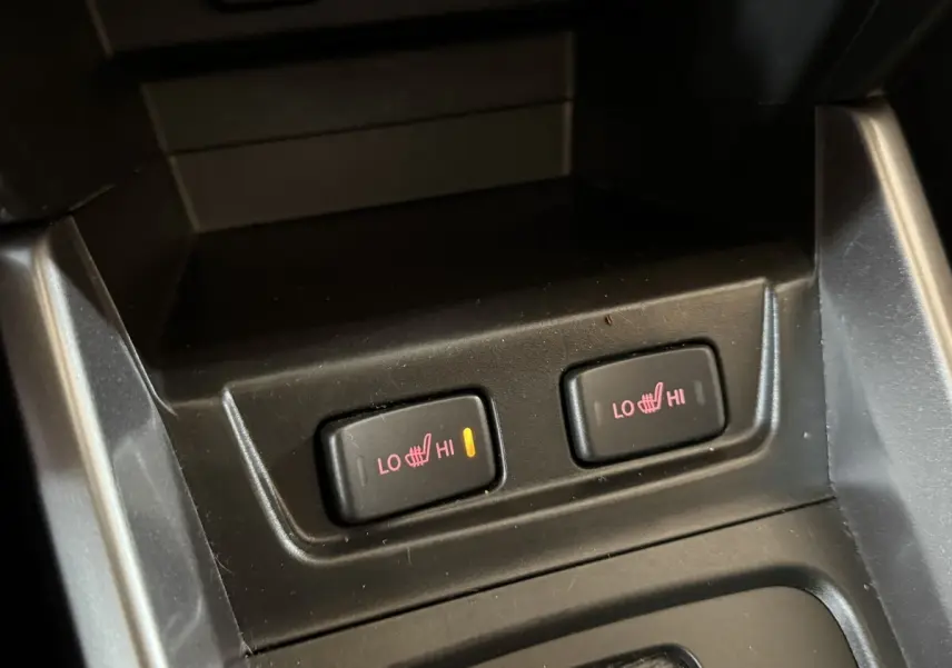 Gros plan sur les commandes de chauffage des sièges avant du Suzuki Vitara noir 2022, bouton gauche activé.