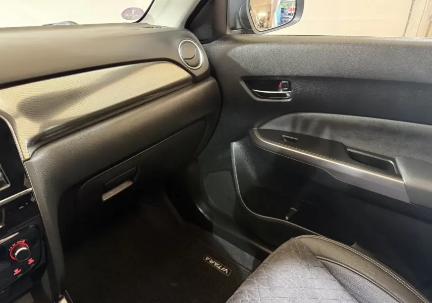 Intérieur côté passager du Suzuki Vitara 1.5 Hybrid 2022, avec tableau de bord noir et siège tissu gris.