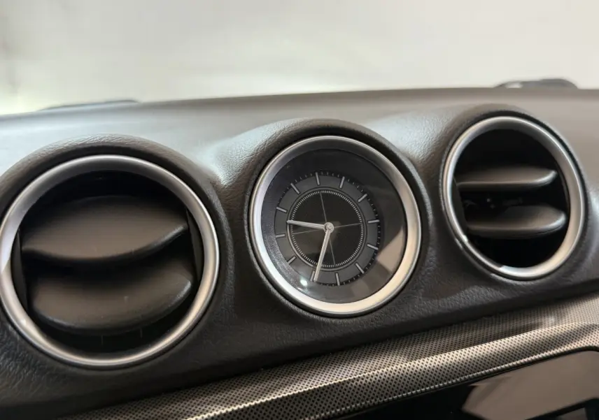 Gros plan sur l'horloge ronde et les aérateurs circulaires du tableau de bord noir du Suzuki Vitara 2022.