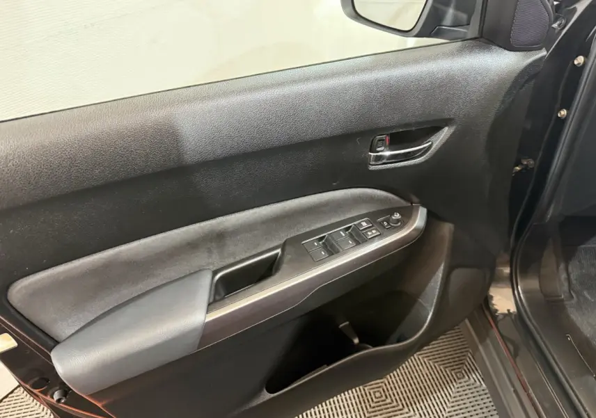 Vue rapprochée de la porte avant gauche noire du Suzuki Vitara 1.5 Hybrid avec commandes électriques et poignée chromée.