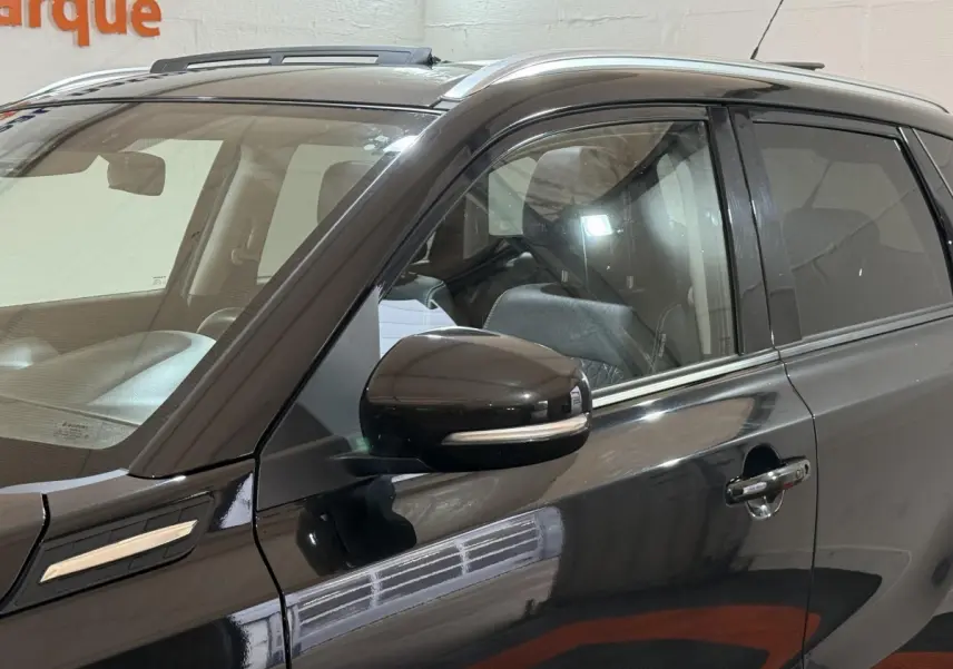 Vue latérale côté gauche du Suzuki Vitara noir 2022 avec rétroviseur et toit ouvrant en verre visibles.