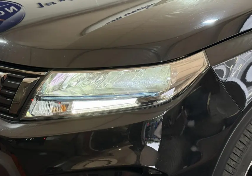 Gros plan sur le phare avant droit du Suzuki Vitara noir 2022, mettant en valeur ses feux LED et la calandre chromée.