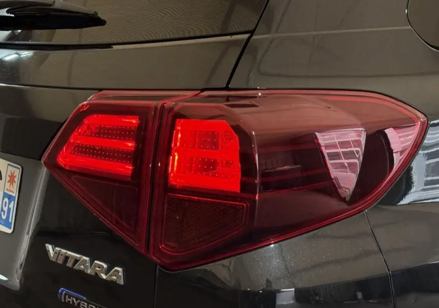 Feu arrière droit rouge sur Suzuki Vitara noir hybride 2022, avec logo VITARA visible près de la plaque arrière.