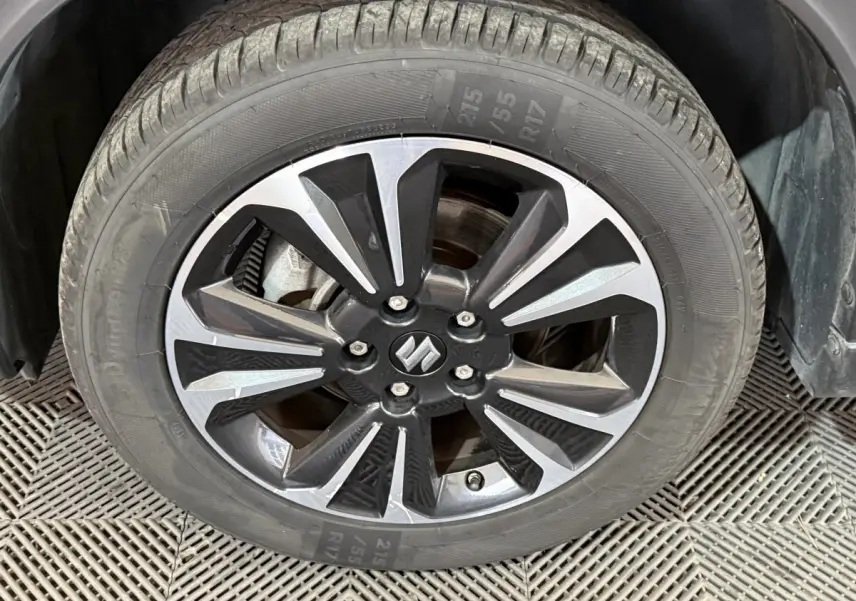 Gros plan sur la jante alliage bicolore noire et argentée avec logo Suzuki du Suzuki Vitara noir 2022.