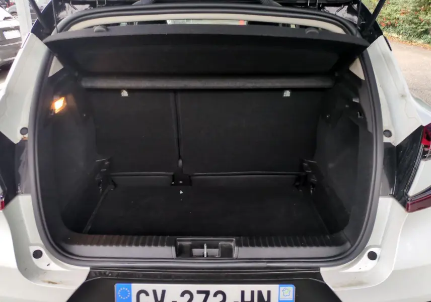 Coffre ouvert d’un Renault Captur blanc vu de l’arrière, montrant un espace de chargement vide et noir.