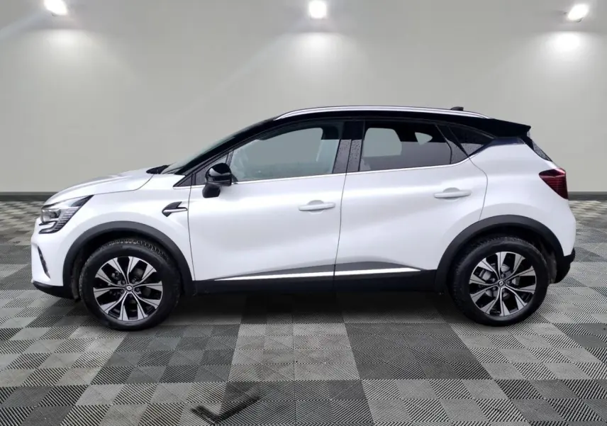 Profil droit d'un Renault Captur blanc 2024 avec toit noir, jantes alliage 18 pouces et protections noires.