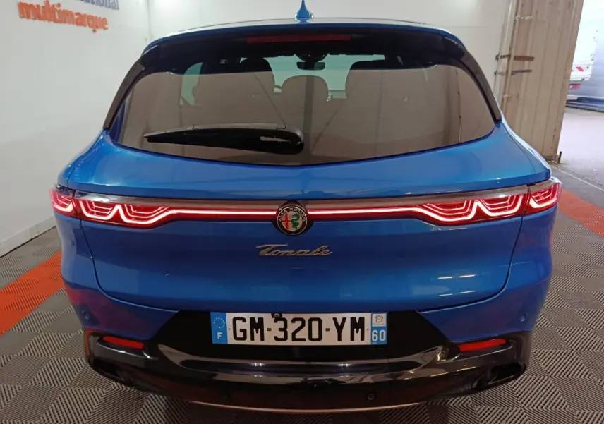 Vue arrière d'une Alfa Romeo Tonale bleu électrique avec feux arrière LED distinctifs allumés.