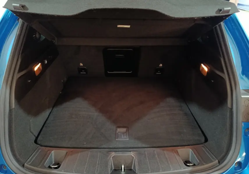 Coffre ouvert de l'Alfa Romeo Tonale bleu 2023, vue arrière montrant l'espace de chargement et l'éclairage intérieur.