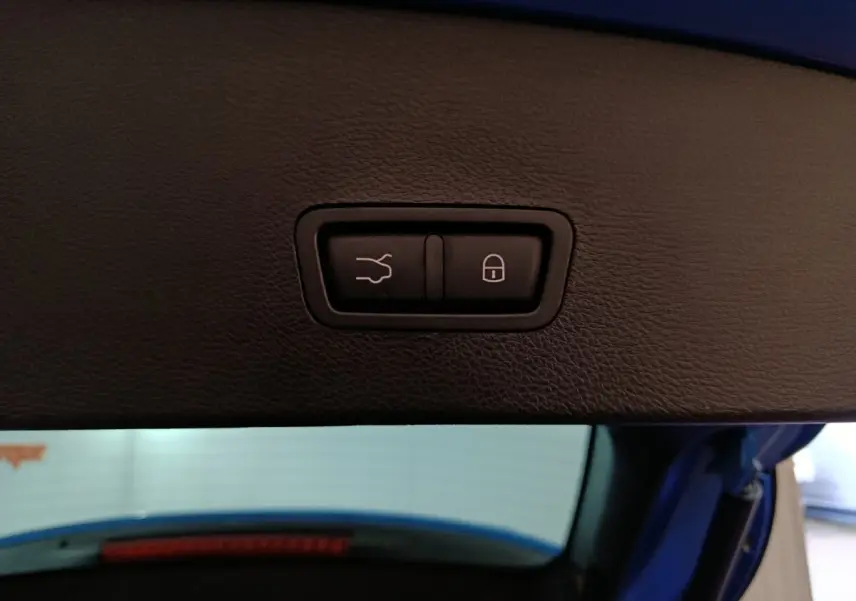 Gros plan sur les boutons d'ouverture et de verrouillage du coffre du hayon d'une Alfa Romeo Tonale bleu.