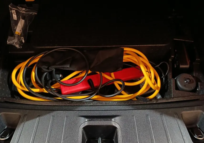 Coffre ouvert d'Alfa Romeo Tonale bleu 2023 montrant câble de recharge hybride rechargeable jaune et noir rangé.