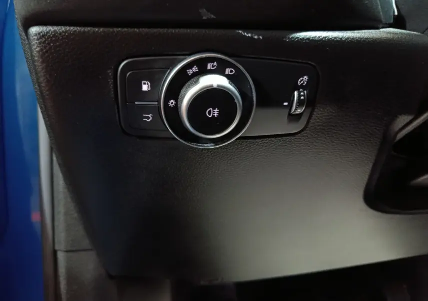 Gros plan sur le bouton de commande des feux sur tableau de bord noir de l'Alfa Romeo Tonale bleu.