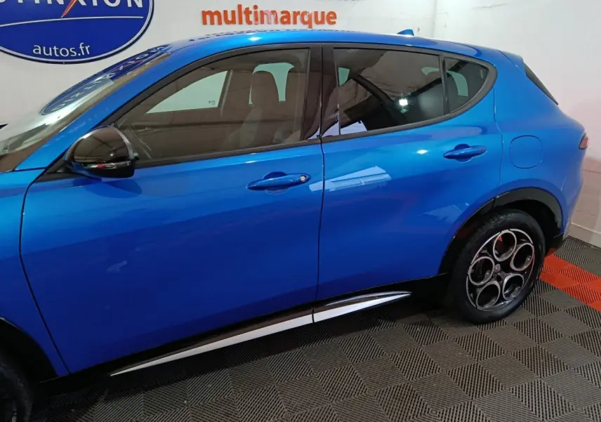 Vue latérale côté gauche d'un Alfa Romeo Tonale bleu 2023 avec jantes distinctives à cinq cercles et poignées de porte ton caisse.