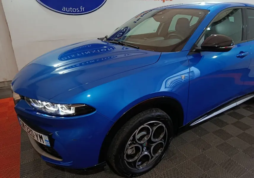 Vue 3/4 avant droit d'une Alfa Romeo Tonale bleu électrique avec jantes spécifiques et badge Ti sur l'aile.