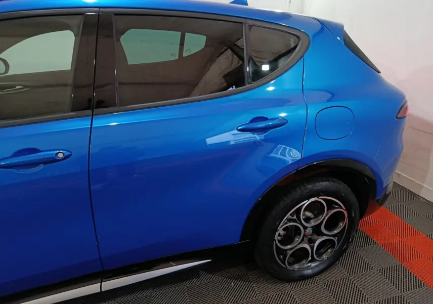 Vue latérale droite d'une Alfa Romeo Tonale 2023 bleu électrique, mettant en valeur la porte arrière et la trappe à carburant.