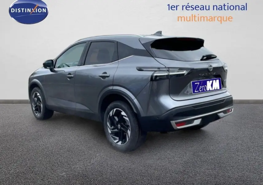 Vue 3/4 arrière droite du Nissan Qashqai gris 2025 avec jantes aluminium et barres de toit visibles.