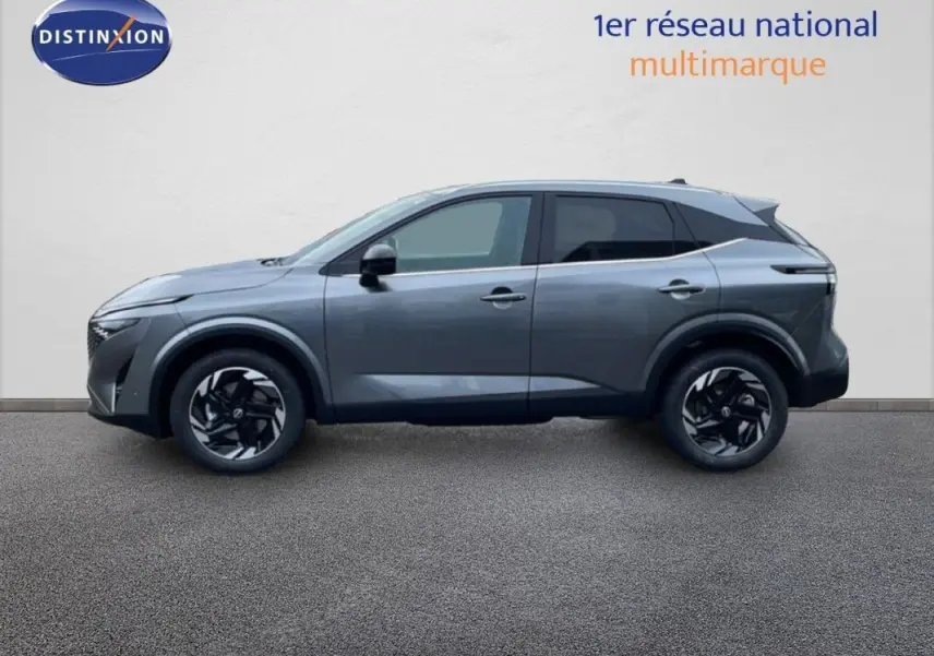 Vue de profil côté gauche d'un Nissan Qashqai gris 2025 avec jantes aluminium et barres de toit visibles.