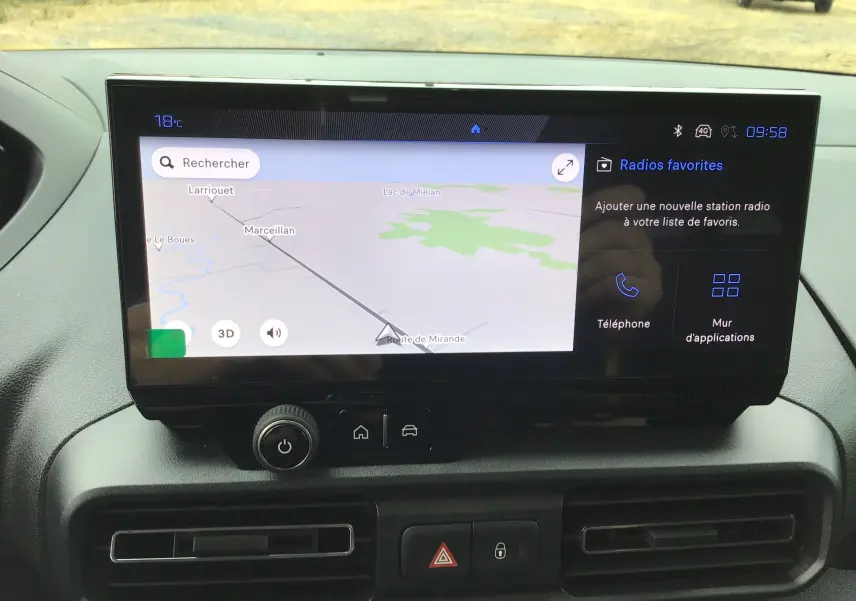 Écran tactile central du Peugeot Partner XL 2026 montrant la navigation GPS et les options radio, avec tableau de bord noir.