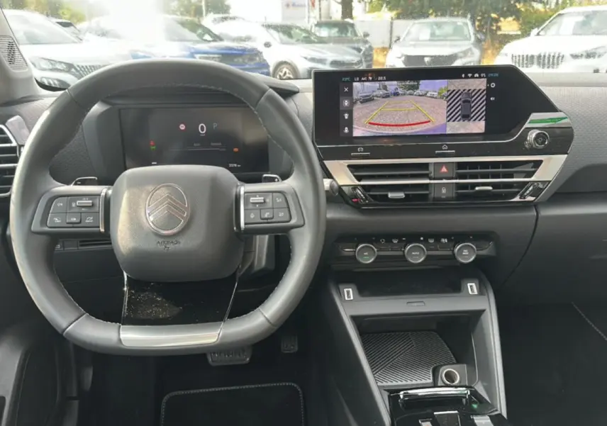 Vue frontale de l'intérieur noir du Citroën C4 X 2025, avec volant cuir et écran tactile affichant la caméra de recul.