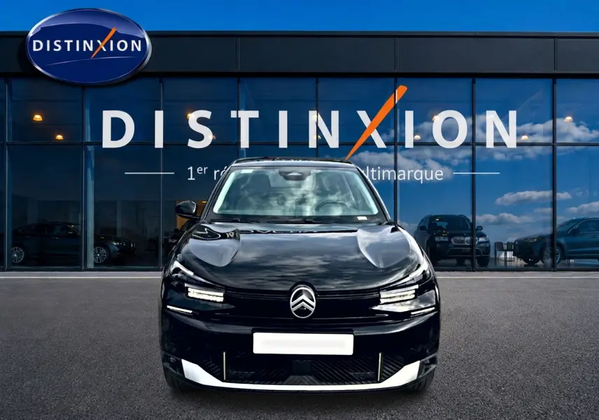 Vue frontale d'une Citroën C4 X noire 2025 avec calandre distinctive et phares LED fins, devant une vitrine Distinxion.