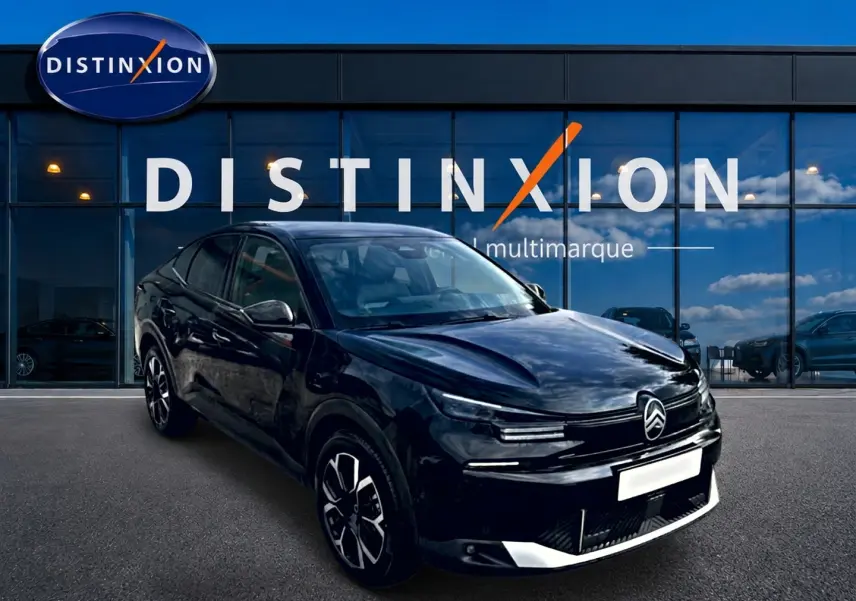 Citroën C4 X noire vue en 3/4 avant droit, avec jantes alu et calandre distinctive devant un showroom Distinxion.