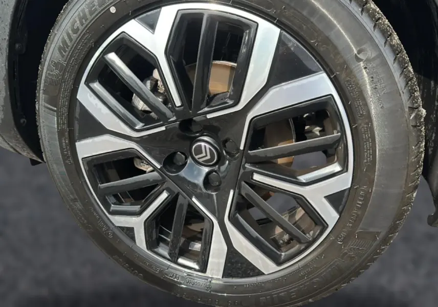 Gros plan sur la jante alu noire et argentée d'une Citroën C4 X noire, vue côté droit.