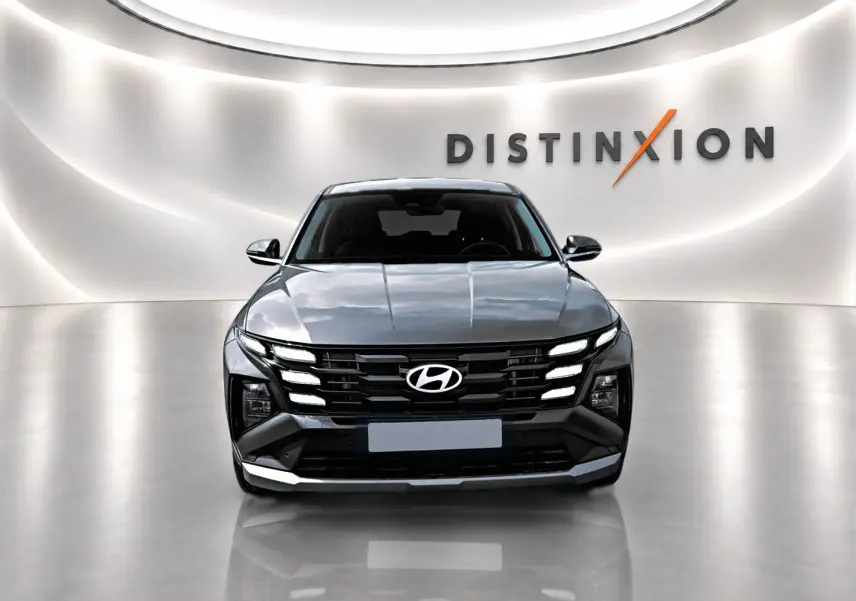 Vue frontale d'un Hyundai Tucson 2026 gris ecotronique avec calandre noire et éclairage LED distinctif, sur fond blanc lumineux.