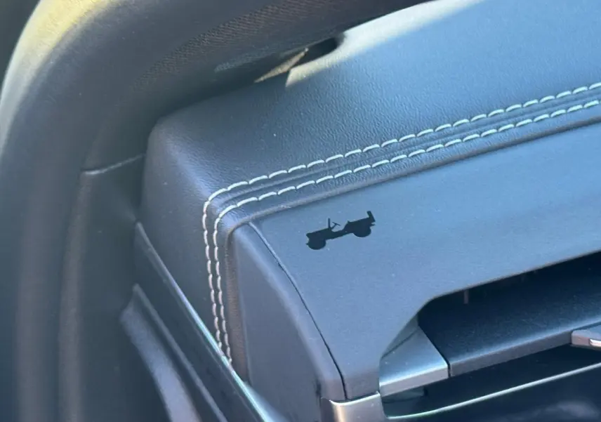 Détail de l’accoudoir central avant en cuir noir avec surpiqûres blanches et logo Jeep silhouette d’un 4x4.