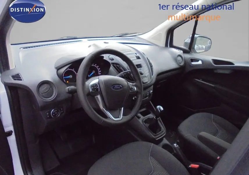 Vue intérieure côté conducteur du Ford Transit Courier blanc glacier 2022, tableau de bord et volant avec boîte manuelle visibles.