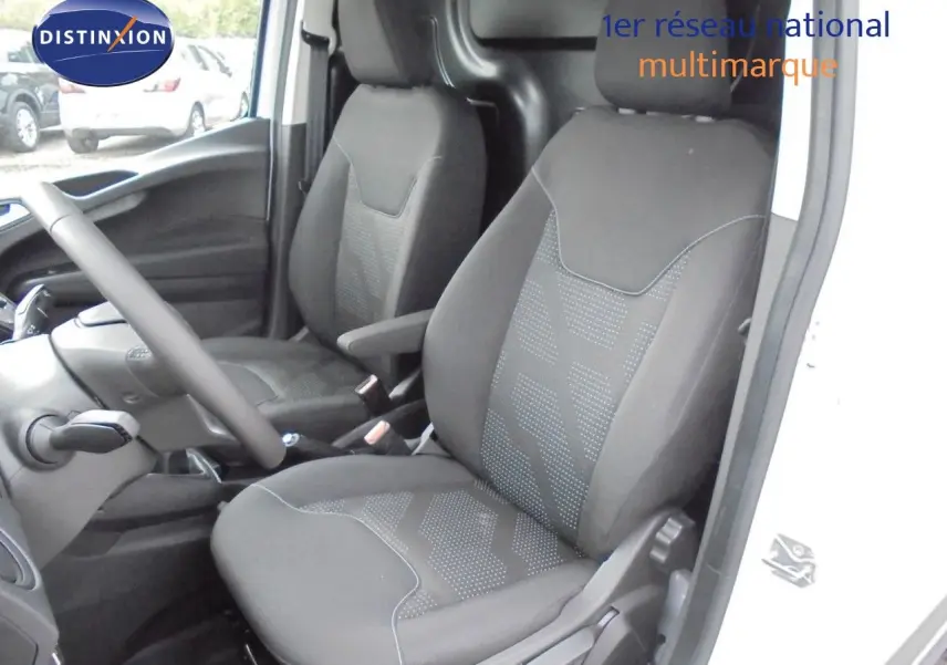 Intérieur du Ford Transit Courier 2022 montrant les sièges avant noirs et la console côté conducteur, porte ouverte côté droit.