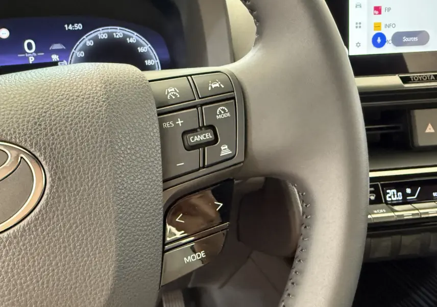 Gros plan sur le volant cuir multifonctions du Toyota C-HR 1.8 Hybride blanc, avec commandes de régulateur et écran tactile visible.