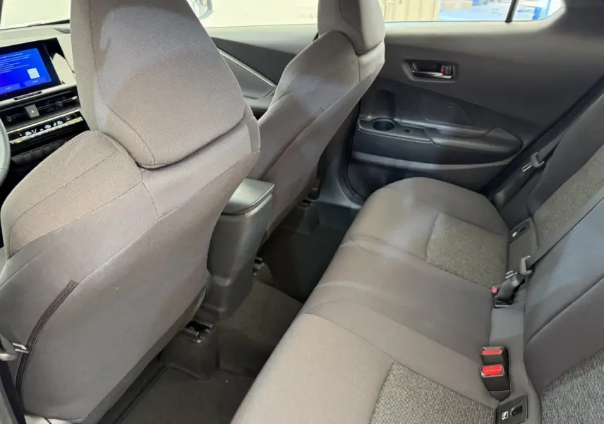 Vue intérieure arrière droite du Toyota C-HR 1.8 Hybride 140 Dynamic 2024 avec sièges tissu gris et console centrale noire.