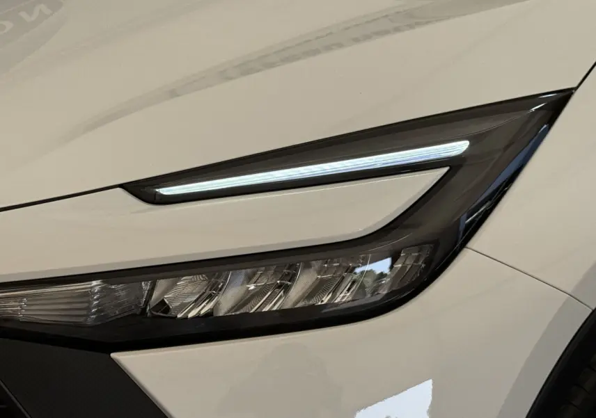 Gros plan sur le phare avant droit LED du Toyota C-HR 1.8 Hybride blanc, soulignant son design affûté.