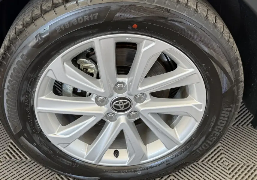 Gros plan sur la jante argentée avec logo Toyota d’un Toyota C-HR blanc, pneu Bridgestone visible.