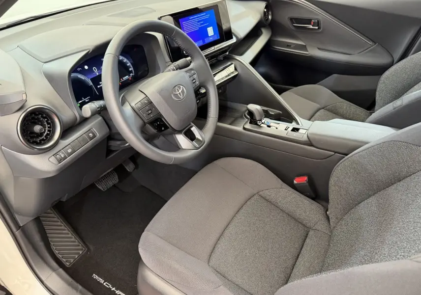 Intérieur avant droit du Toyota C-HR 1.8 Hybride 2024 avec tableau de bord gris et écran tactile central.
