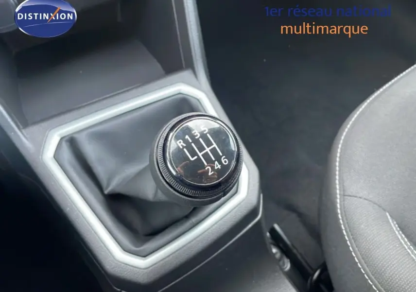 Gros plan sur le levier de vitesses manuel du Dacia Jogger gris schiste métal, avec coutures visibles sur le siège noir à côté.