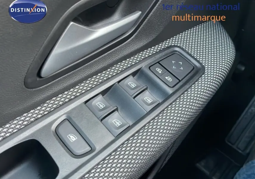 Gros plan sur la commande des vitres côté conducteur avec tissu gris à motifs dans une Dacia Jogger 2025.