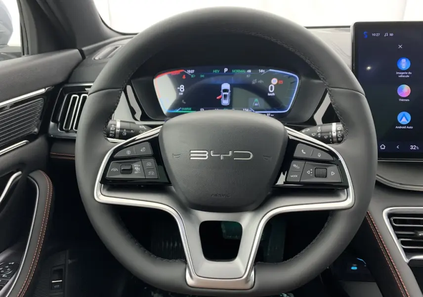 Vue intérieure centrée sur le volant noir du BYD SEAL U 2025 avec tableau de bord numérique et écran tactile latéral.