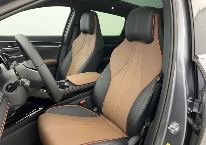 Vue intérieure côté conducteur du BYD SEAL U 2025 avec sièges en similicuir bicolore noir et marron, surpiqûres orange et toit ouvrant panoramique.