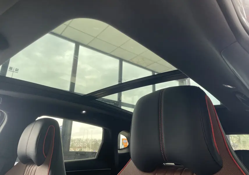 Vue intérieure du toit ouvrant panoramique et des sièges avant noirs avec surpiqûres rouges du BYD SEAL U TIME GREY 2025.