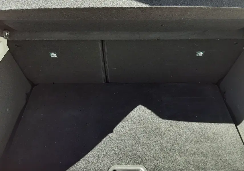 Coffre ouvert vu de l'arrière d'une Renault Clio V rouge, montrant un espace de chargement vide et propre.