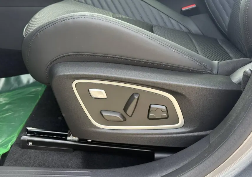 Gros plan sur les commandes électriques du siège conducteur en cuir noir du Renault Austral 2026, version hybride.