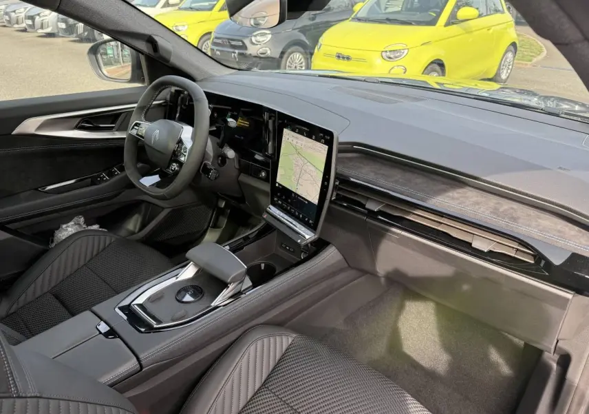 Vue intérieure côté conducteur du Renault Austral 2026, tableau de bord noir avec écran tactile vertical et sièges en tissu carbone Alcantara.